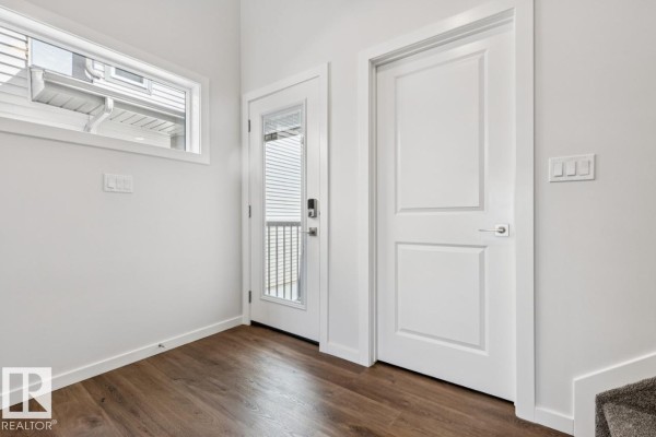 Living area adjacent to the kitchen with a white island, grey walls, and a light fixture. - 50 Gambel Lo, Spruce Grove