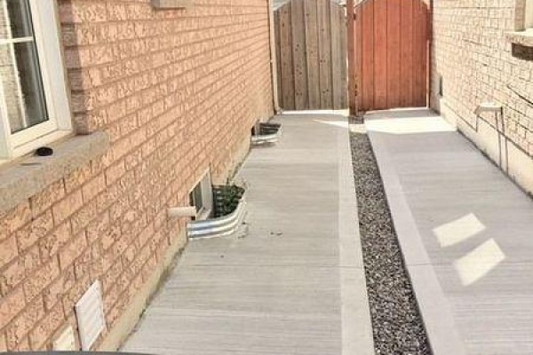 Side view of a brick house with a wooden gate and concrete pathway. - 50 Geddington Crescent, Markham