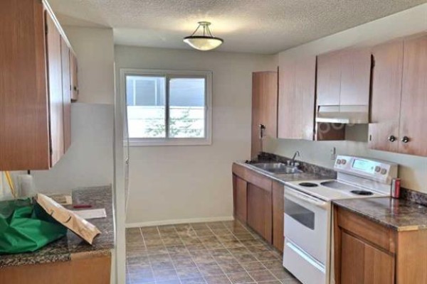 Kitchen with light wood cabinets, granite countertops, white stove, and sink overlooking a window. - 50 Jerry Potts Boulevard W, Lethbridge