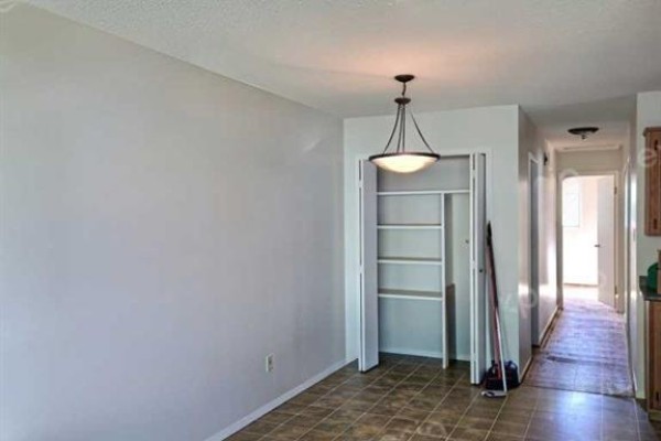 Interior hallway with a closed closet, tiled floor, and doorway leading to another room. - 50 Jerry Potts Boulevard W, Lethbridge