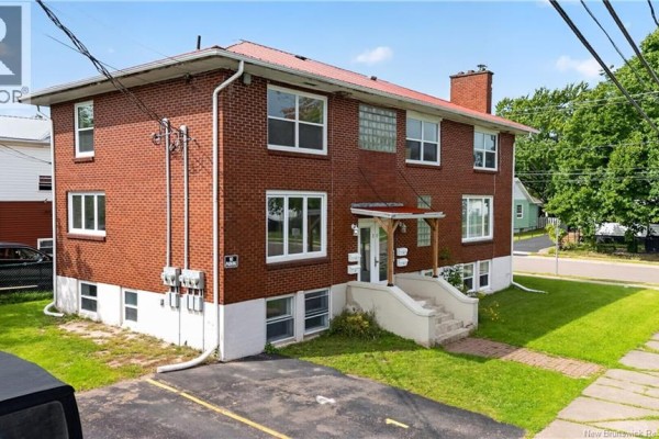 Side view of the red brick multi-family building with white-trimmed windows and concrete stairs. - 50 Leslie, Moncton