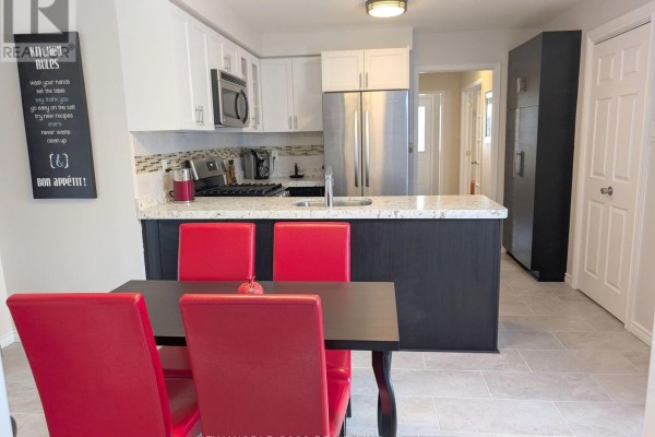 Modern kitchen with island, stainless steel appliances, and red dining chairs - 50 Livingstone Street W Barrie