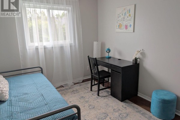 Bedroom with blue bed, black desk, and ottoman - 50 Livingstone Street W Barrie