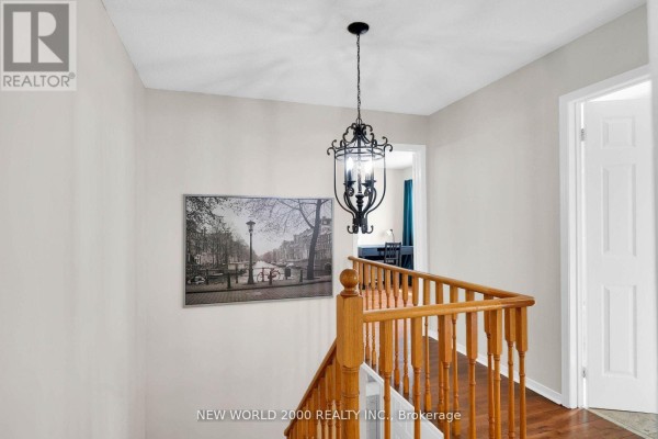 Hallway with ornate chandelier, canal art, and wooden banister - 50 Livingstone Street W Barrie