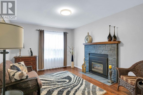 Living room with stone fireplace, hardwood floors, zebra rug, and wicker chair - 50 Livingstone Street W Barrie