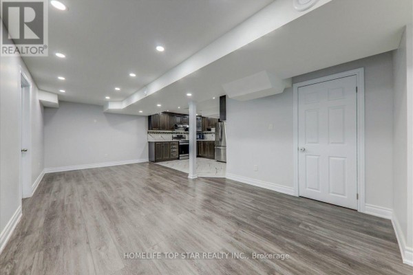 Finished basement with white walls, gray laminate and white marble tile floors, and kitchen area. - 50 Marydale Avenue S, Markham