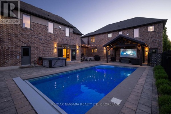 Aerial view of a brick backyard featuring a swimming pool, hot tub, basketball court, and covered patio. - 50 Sandalwood Crescent, Niagara On The Lake