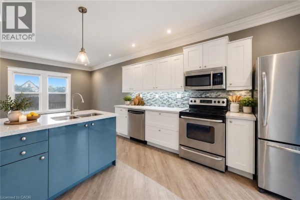 Modern kitchen with white upper cabinets, blue island, stainless steel appliances, and white quartz countertops. - 50 Somerset Avenue, Hamilton