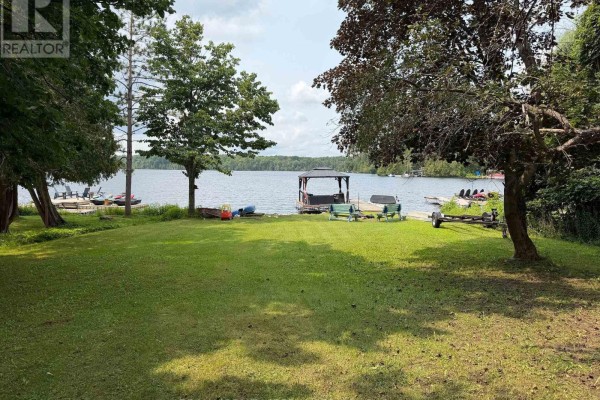 Living and dining area with wood-paneled walls, television, and bar. - 50 South Fork Drive, Kawartha Lakes