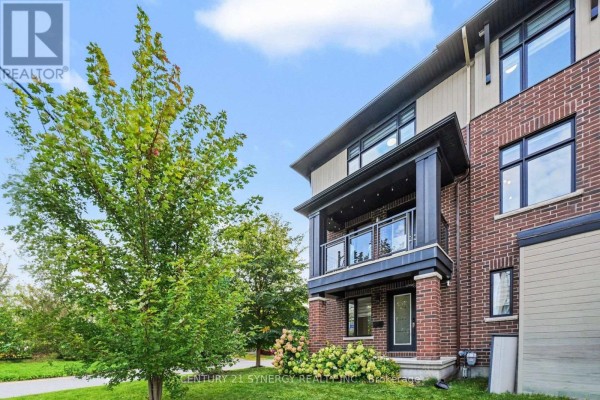 Right side exterior view of brick townhouse with balconies, dark wood accents, and large windows. - 50 Spicebush Place, Ottawa