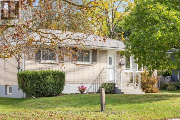 Side exterior view of the bungalow with mature trees and manicured bushes. - 50 St David Street, Kawartha Lakes