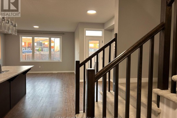 Interior view showing hardwood floors, a staircase with dark wood railings, and a large window. - 50 Stokes Drive, Carleton Place