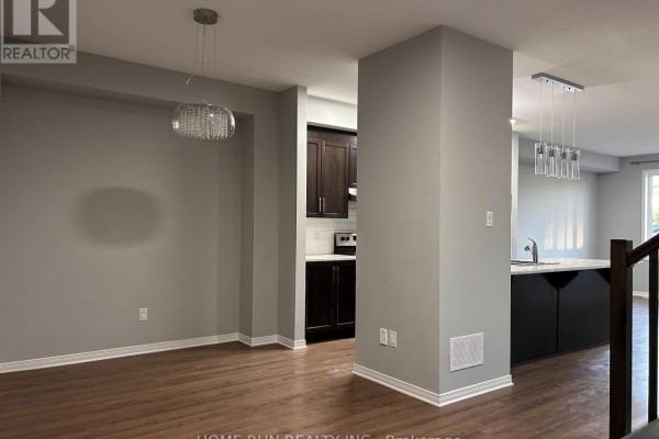 Open concept living area with gray walls, wood floors, and a kitchen island with dark cabinets. - 50 Stokes Drive, Carleton Place