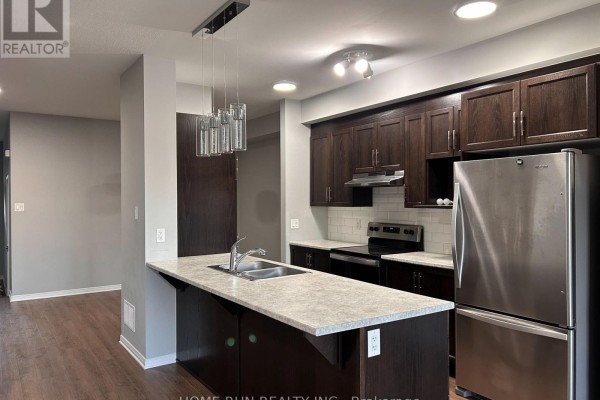 Kitchen with dark wood cabinets, stainless steel appliances, a kitchen island with a double sink. - 50 Stokes Drive, Carleton Place