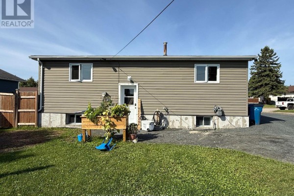 Backyard with a grassy lawn, inflatable pool, patio furniture, and a raised garden box. - 50 Victoria Avenue, Cochrane