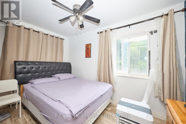 Bedroom with a queen-size bed, ceiling fan, air conditioning unit, and window. - 50 Welland Avenue, St  Catharines