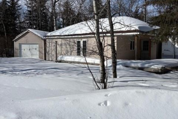 Living room featuring a brown sectional sofa and wood stove - 500 Amisk Lane, Turtle Lake