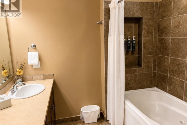 Bathroom with a bathtub, tiled walls, a sink with a countertop, and a white shower curtain. - 500 Bighorn Boulevard Unit# 521, Radium Hot Springs