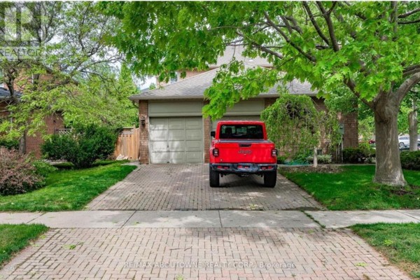 Driveway view of the home with a red vehicle parked in front of the garage - 500 Blenheim Crescent, Oakville
