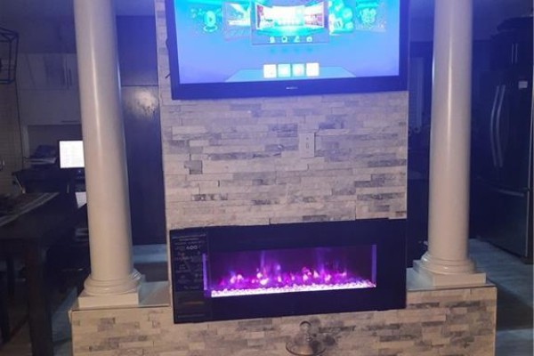 Modern fireplace with stacked stone surround and a television mounted above, flanked by white columns. - 500 Snowdrop Court Unit# Upper, Kitchener