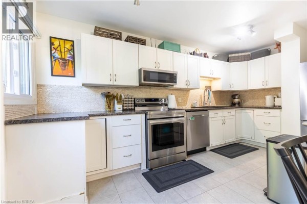 Kitchen with white cabinets, stainless steel appliances, and dark speckled countertops. - 500 Stone Church Road W Unit# E5, Hamilton