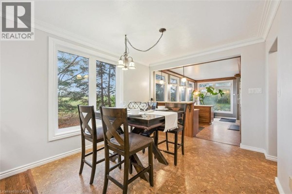 Dining area with a dark wood table and view into the kitchen. - 500 Watson Parkway S, Guelph