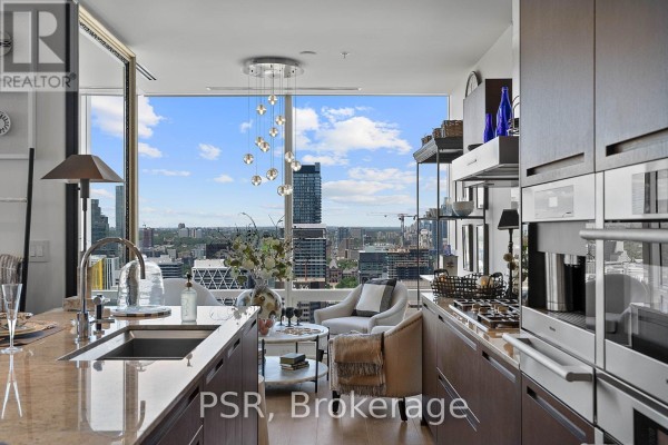 Kitchen with stainless steel appliances, granite countertops, a sink, and a view of the city skyline. - 5003 - 180 University Avenue, Toronto