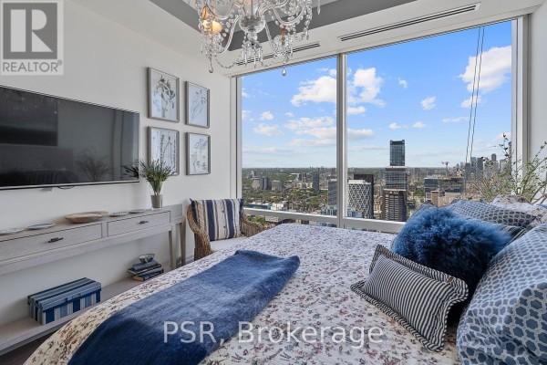 Bedroom with a large bed, city view through floor-to-ceiling windows, and a television on the wall. - 5003 - 180 University Avenue, Toronto