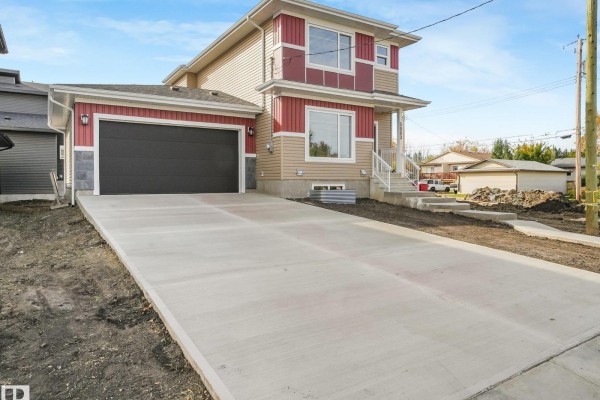 Exterior of a two-story home with red and tan siding, a double garage, and a concrete driveway. - 5003 51 Av, Calmar