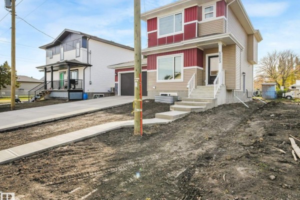 Exterior view of a two-story home with red and tan siding, showing the driveway and neighboring houses. - 5003 51 Av, Calmar