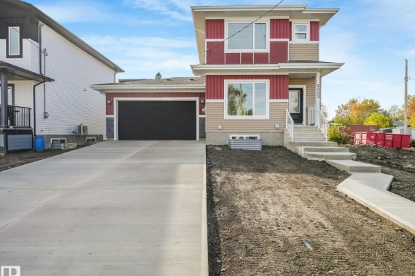 Front view of a two-story home with red and tan siding, a double garage, and a concrete driveway. - 5003 51 Av, Calmar