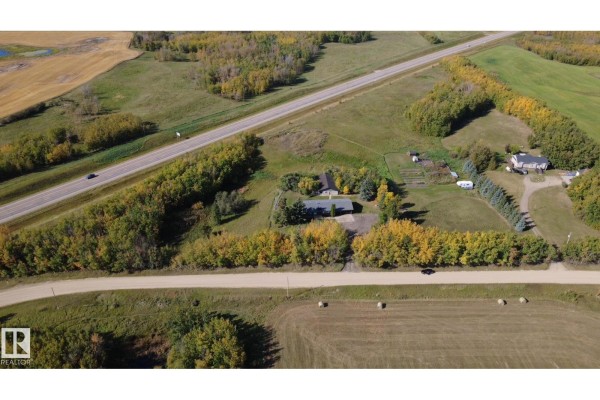 Aerial view of a residential property with a house, outbuilding, and surrounding fields. - 50034 Rge Rd 225, Rural Leduc County
