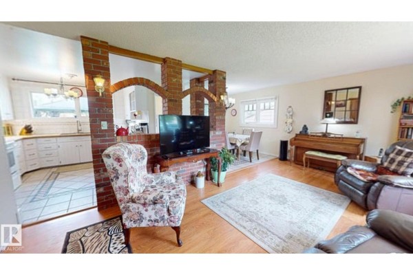 Rear exterior of house with wooden deck, green lawn, and trees. - 5004 50 Av, Evansburg