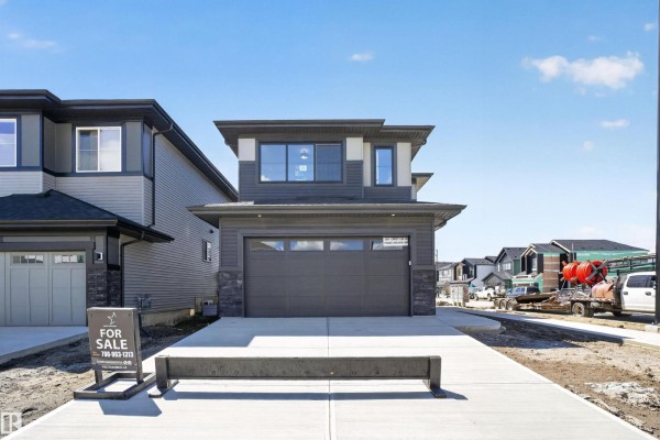 Exterior front view of the modern house at twilight with warm interior lights visible. - 5004 Cawsey Li Sw, Edmonton