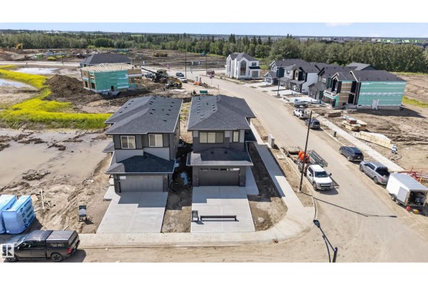 Aerial view of two newly constructed houses on a street with surrounding homes under construction. - 5004 Cawsey Li Sw, Edmonton