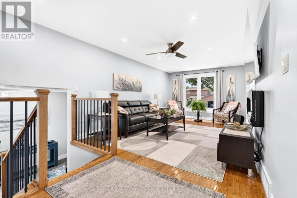 Entryway with light grey walls, tiled floor, wooden staircase with black railings, and a blue console table. - 5004 Pettit Avenue, Niagara Falls