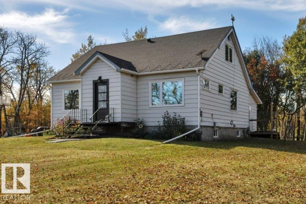 Side view of a light-colored, vinyl-sided house with a dark roof and several windows. - 50040 Rge Rd 230, Rural Leduc County