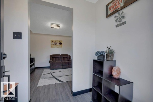 Interior view of a hallway with gray walls, leading into a living room with a sofa. - 50040 Rge Rd 230, Rural Leduc County