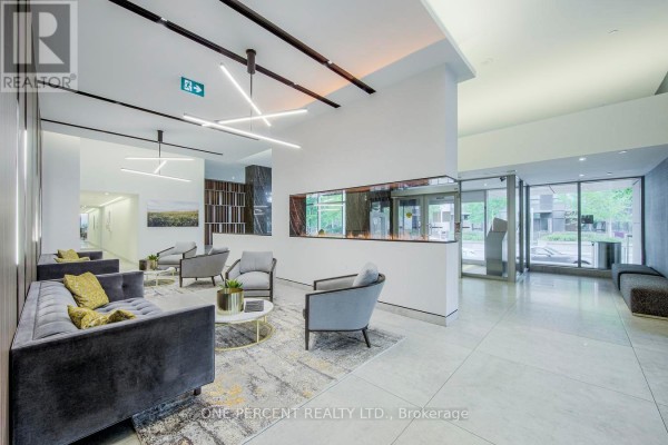 Apartment building lobby with grey sofas, chairs, modern fireplace, and artwork. - 5007 - 25 Telegram Mews, Toronto