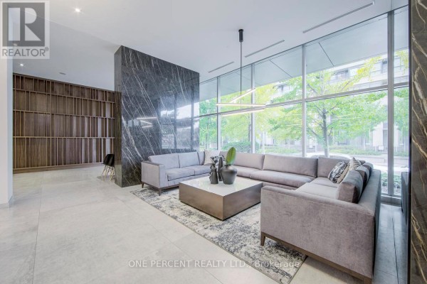 Spacious apartment lobby with large sectional sofa, contemporary art, and floor-to-ceiling windows. - 5007 - 25 Telegram Mews, Toronto
