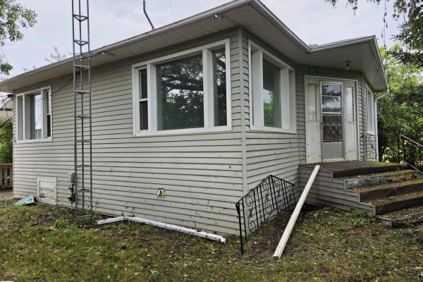 Front view of a light grey vinyl-sided house with a covered porch and steps. - 5007 51 Av, Newbrook