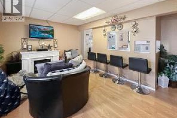 Waiting area with black chairs, a TV, decorative fireplace, and seating. - 5009 50, Valleyview