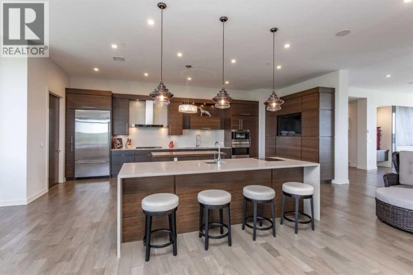 Spacious kitchen with an island, stainless steel appliances, and dark wood cabinetry. - 501, 5002 55th Street, Red Deer