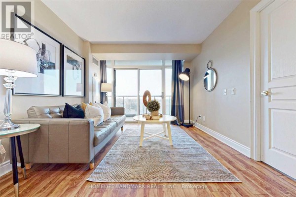Living room with a grey sofa, coffee table, patterned rug, and large windows. - 501 - 10 Northtown Way, Toronto