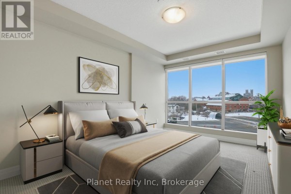 Bedroom with bed, nightstands, and a large window with city view. - 501 - 150 Wellington Street E, Guelph