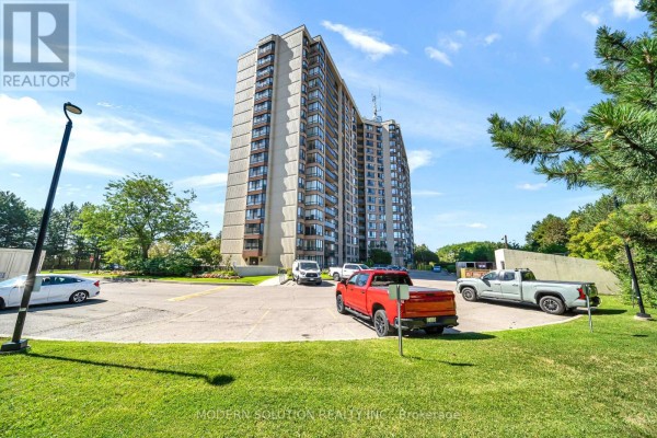 Apartment building entrance with cars parked in the lot. - 501 - 20 Cherrytree Drive, Brampton