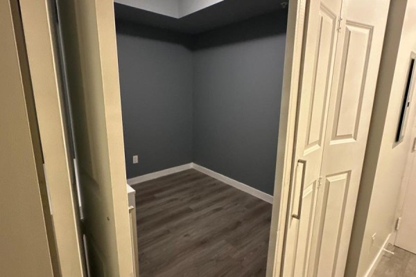 Empty room with dark gray walls, white trim, and wood-look flooring, viewed through an open doorway. - 501 - 318 Spruce Street, Waterloo