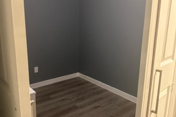 Empty room with dark gray walls, white trim, and wood-look flooring, viewed through an open doorway. - 501 - 318 Spruce Street, Waterloo