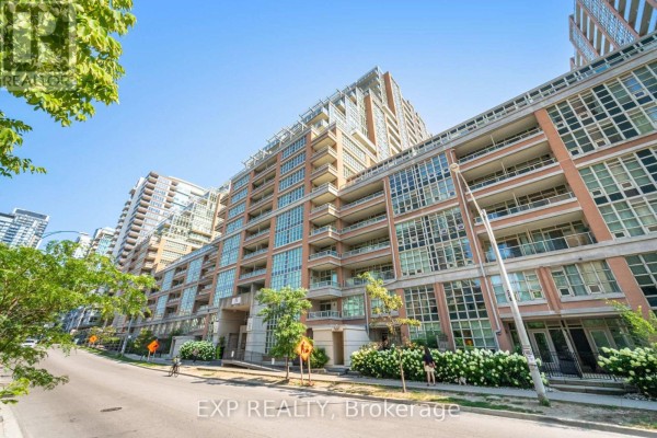 Exterior view of a multi-story brick and glass apartment building on a sunny day with trees. - 501 - 75 East Liberty Street, Toronto