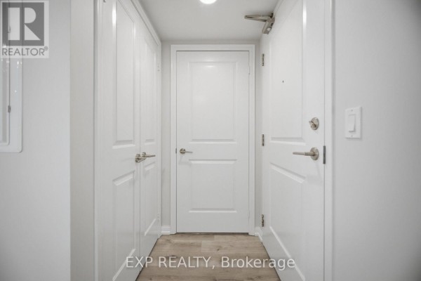 Interior hallway with white doors and trim, featuring built-in closets and light wood flooring. - 501 - 75 East Liberty Street, Toronto